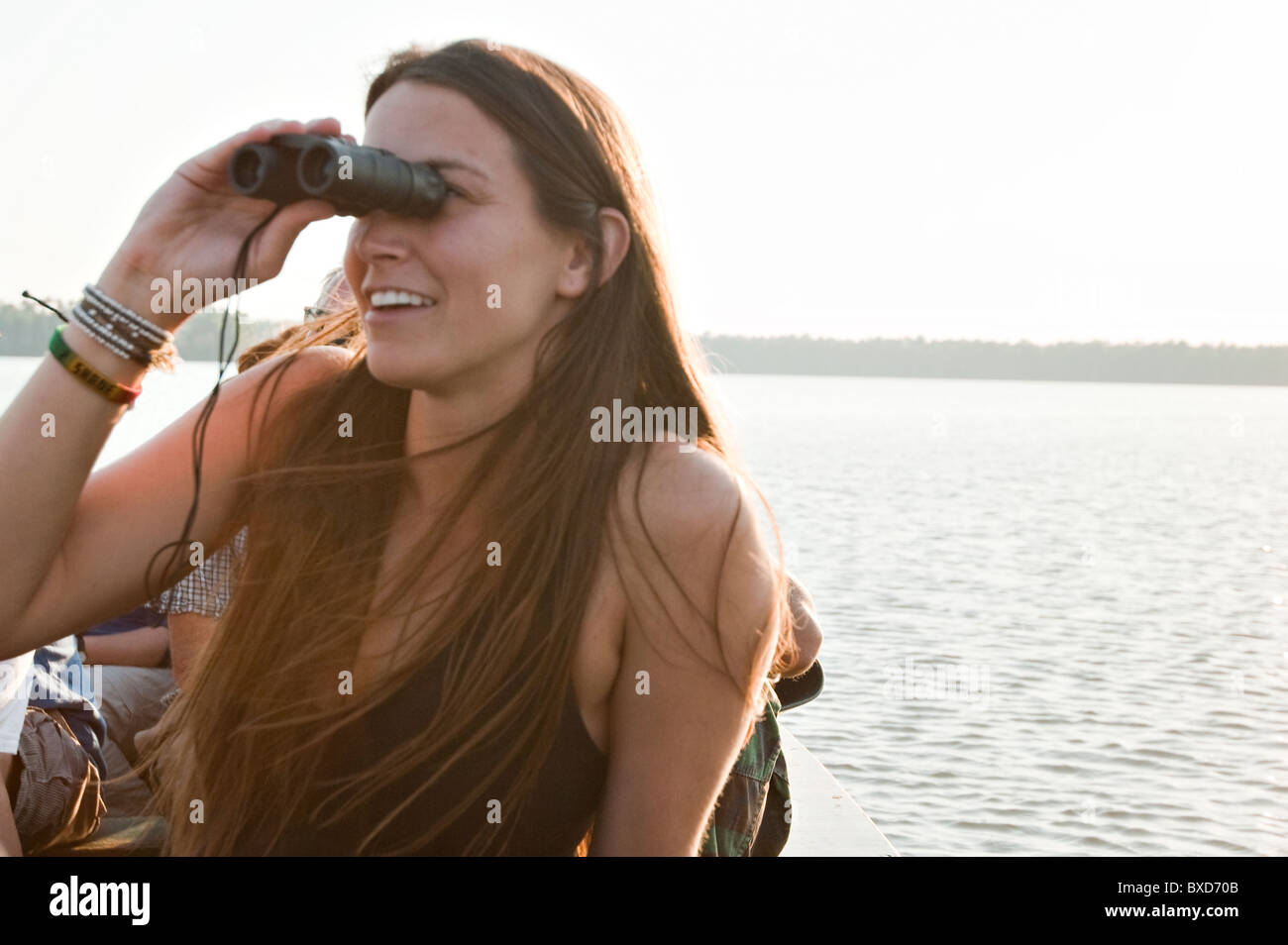 Eine junge Frau schaut durch ein Fernglas auf verschiedenen Arten der Vögel auf Sandoval See im Amazonas-Regenwald. Stockfoto