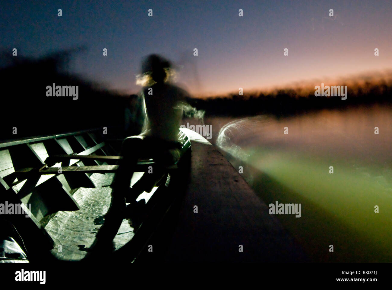 Dorian SImon Paddel eine große hölzerne Kanu bei Sonnenuntergang in Sandoval See. Stockfoto