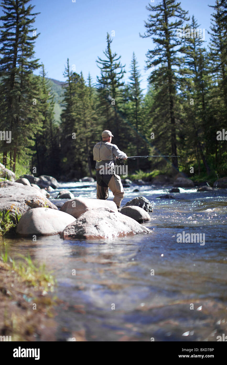 Fischer von den Felsen stehend geht Fliegenfischen an einem Fluss in Vail. Stockfoto