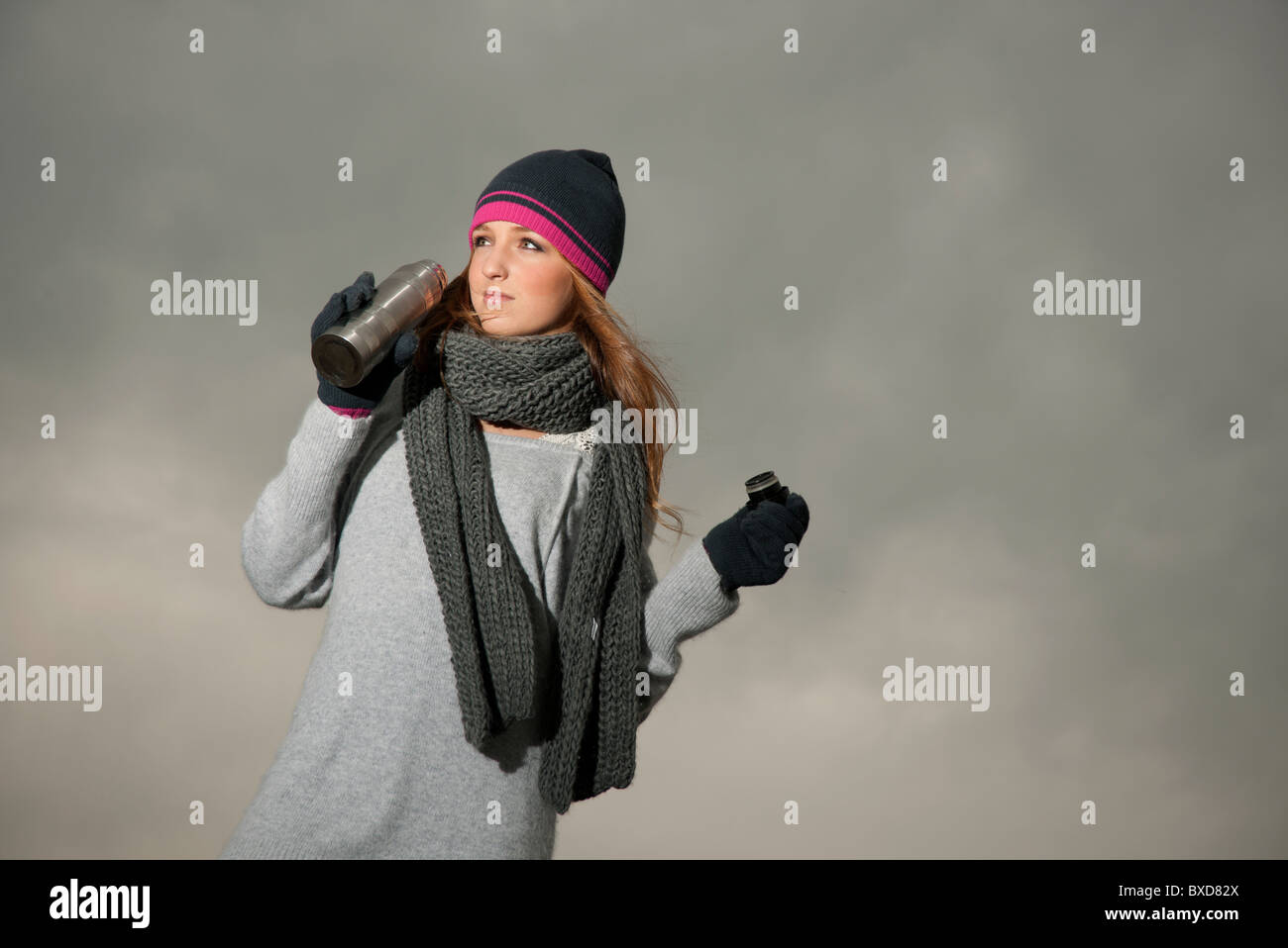 Frau trinkt aus einer Thermoskanne an einem kalten Herbsttag. Stockfoto