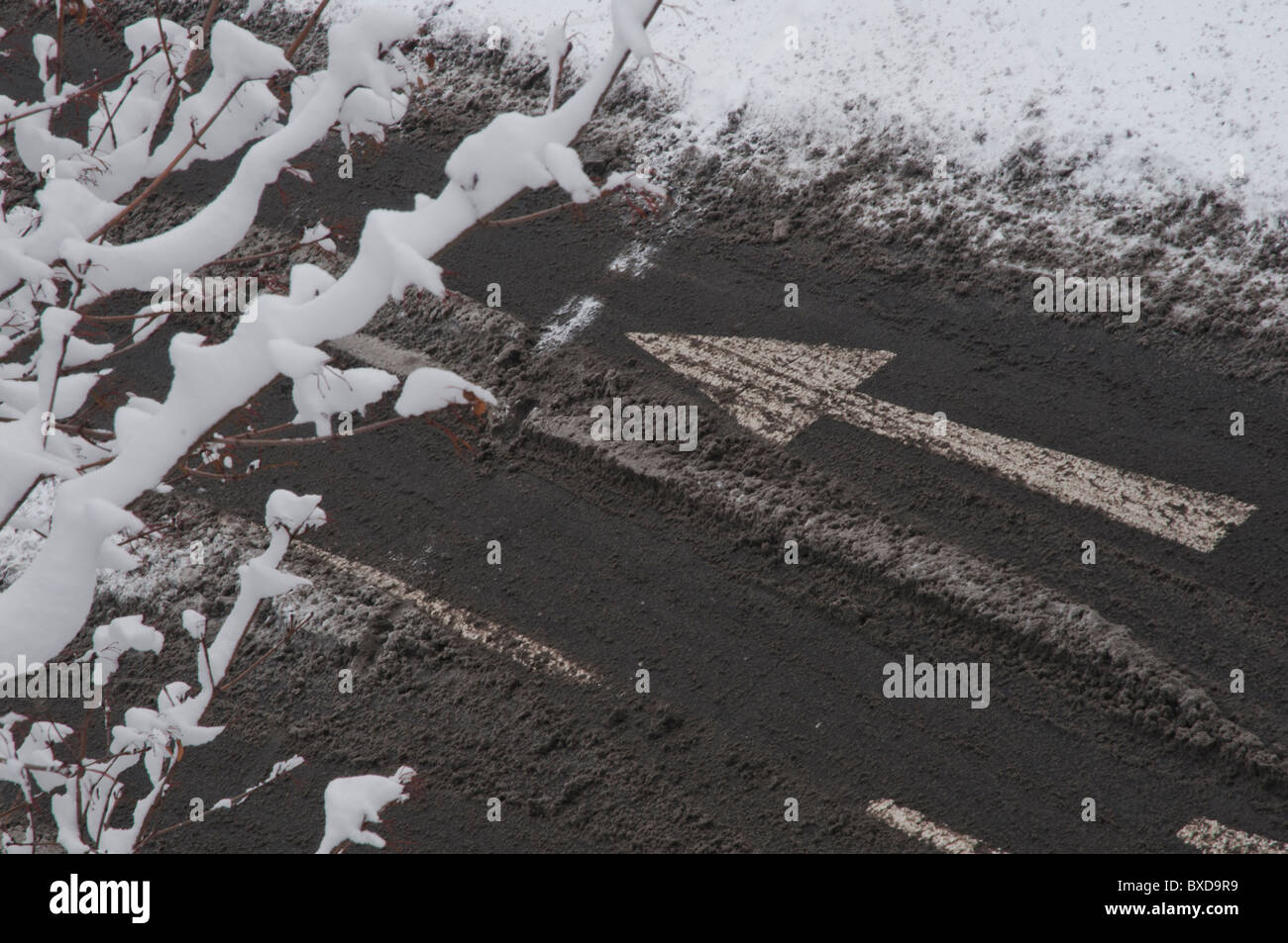 Straßenmarkierungen Pfeil Verkehr in Matsch und Schnee bedeckt Straße Stockfoto