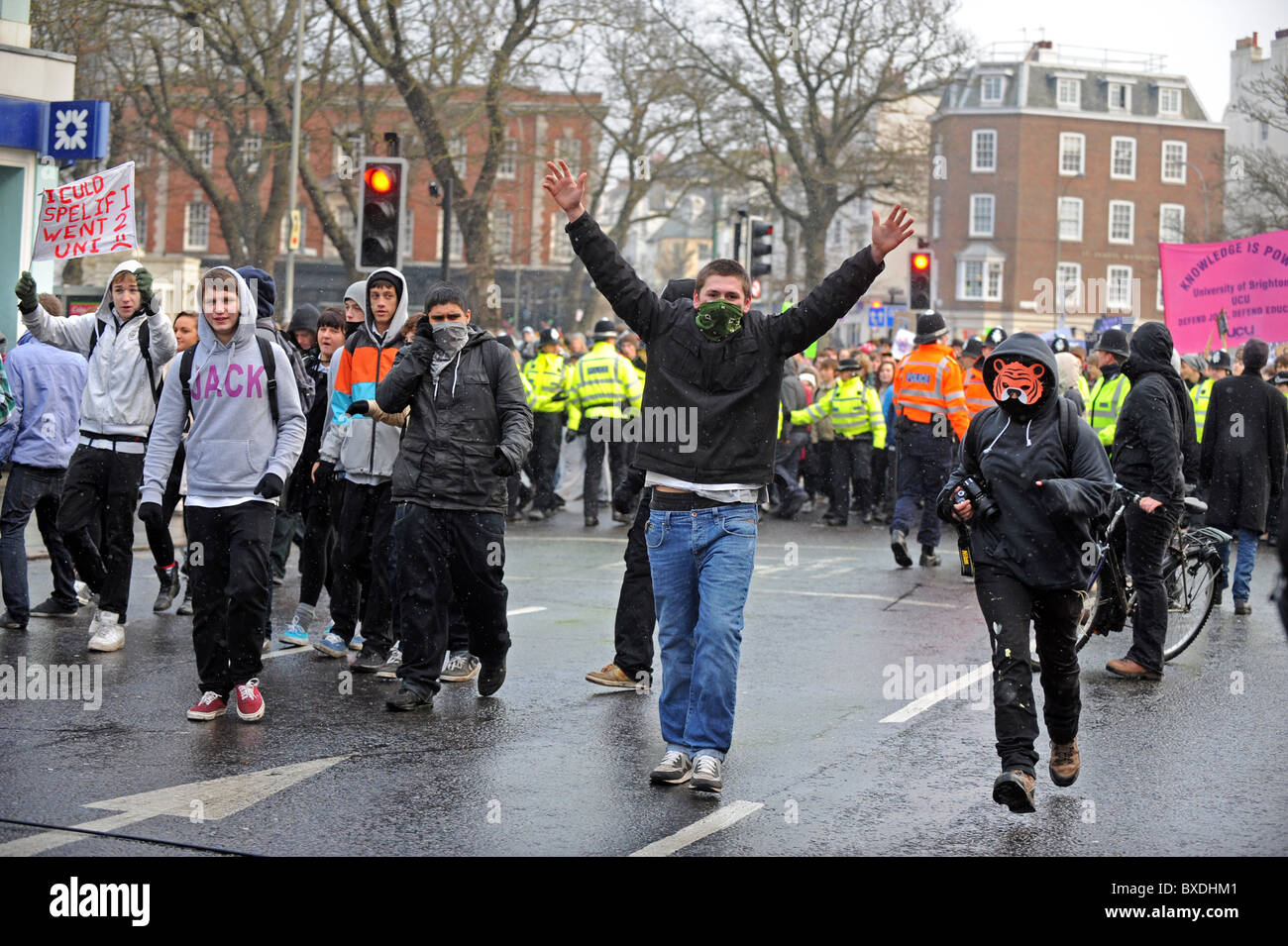 Masse Demonstration in Brighton gegen Regierung Kürzungen der Hochschulfinanzierung - maskierte Demonstranten gehen vor der Polizeiabsperrung Stockfoto