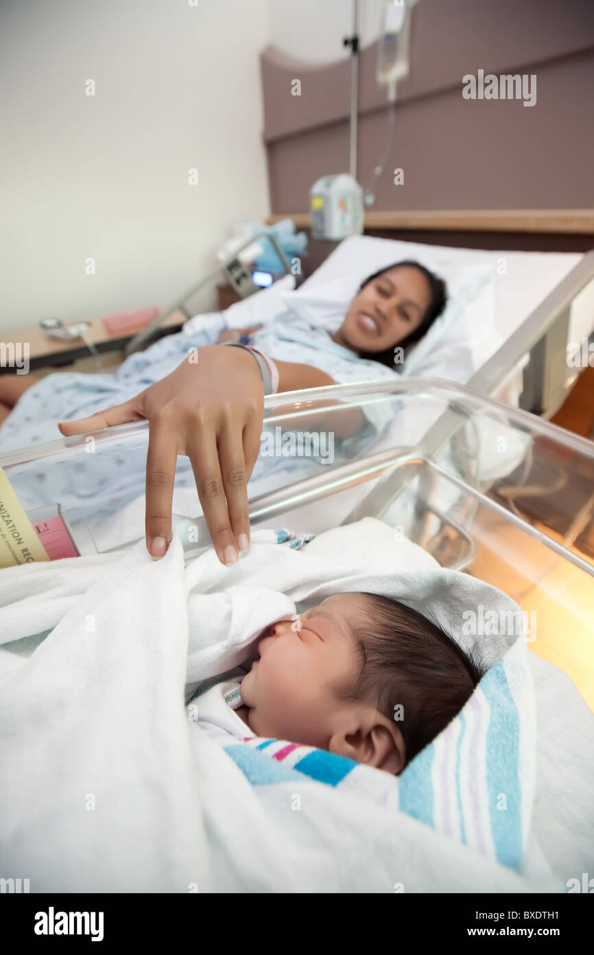 Eine junge Latina Mutter in einem Krankenhausbett mit ihrem Neugeborenen Baby. Stockfoto