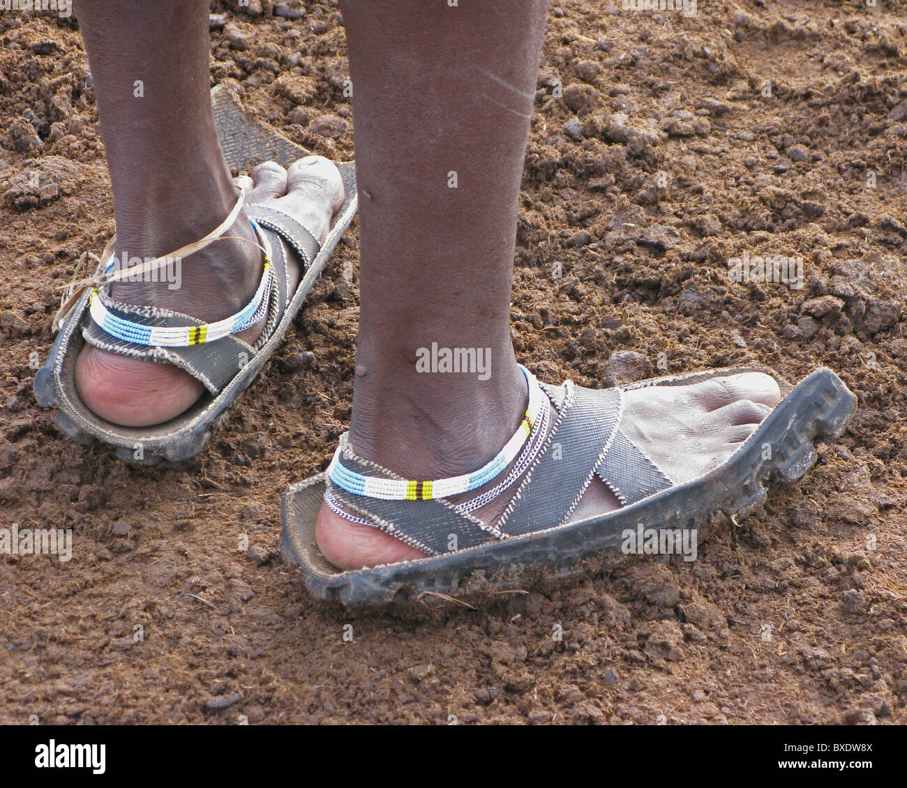 Ein Massai-Krieger trägt Sandalen aus recycelten Motorrad-Reifen, die nur  Schuhe, die sie haben. Andere gehen barfuß Stockfotografie - Alamy