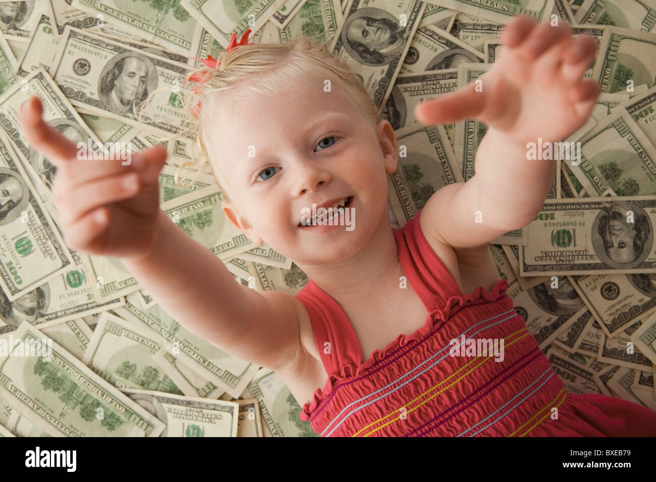 Junges Mädchen auf einen Haufen Geld liegen Stockfoto