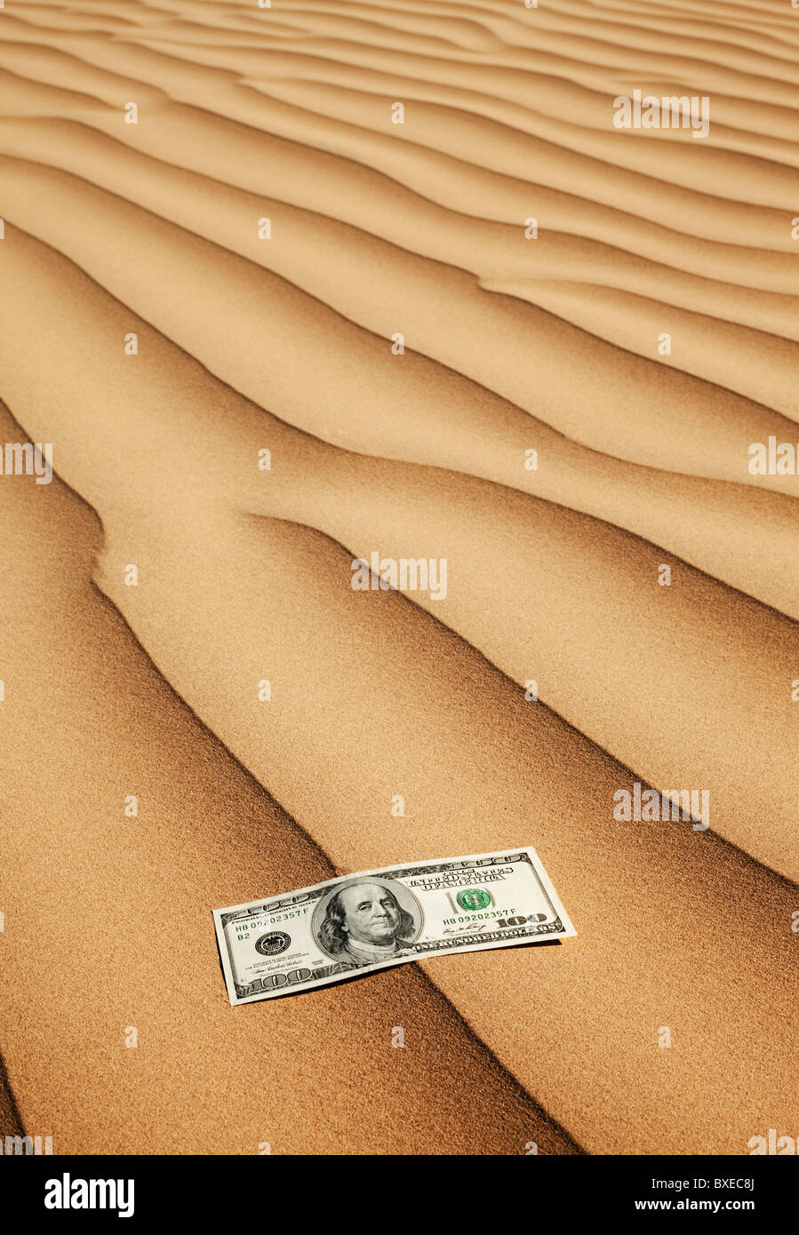 100 Dollar-Schein auf Sand in der Wüste Stockfoto