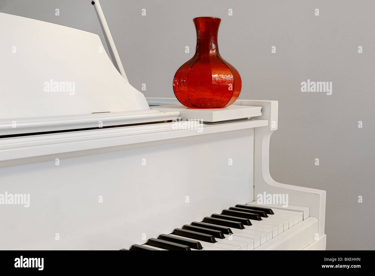 Ecke eines Klaviers mit einer roten Vase in einem Wohngebäude. Stockfoto
