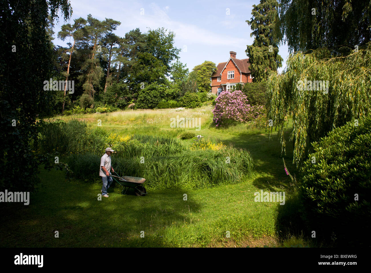 Freiwilligen Gärtner schiebt Schubkarre während der Arbeit Exerzitien in Bruchtal buddhistischen Retreat-Zentrum, East Sussex, England. Stockfoto