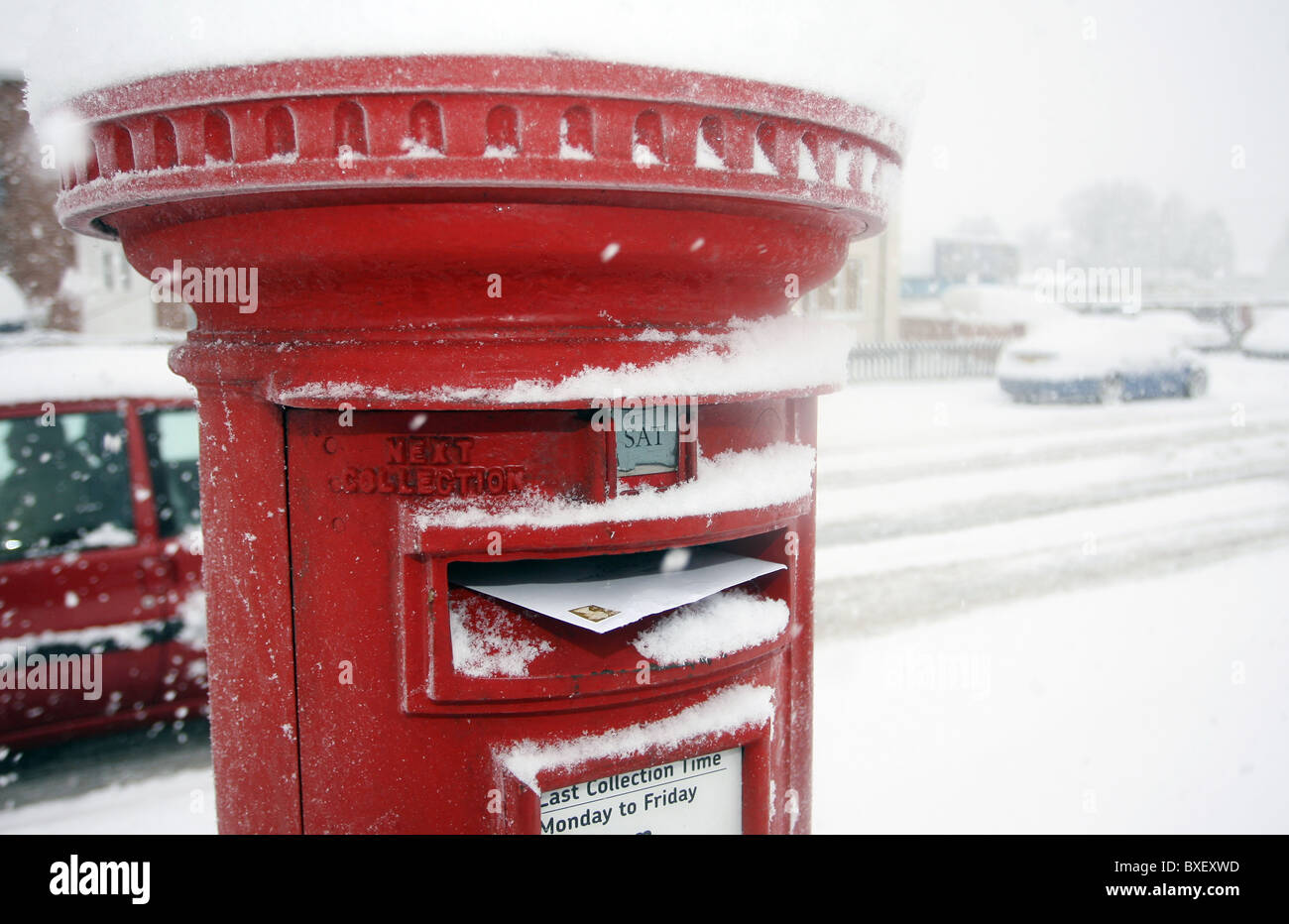 Eine rote britische Postfach überfüllt mit Mail mit Schnee bedeckt Stockfoto