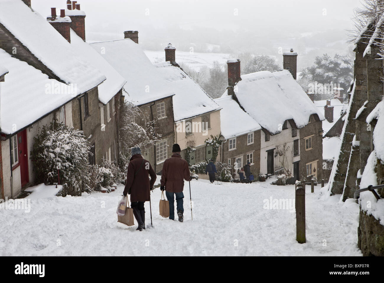 Zwei Menschen, die sorgfältig ihren Weg bergab Gold in Dorset im Schnee auf einem Dezembermorgen. Menschen nicht erkennbar. Stockfoto