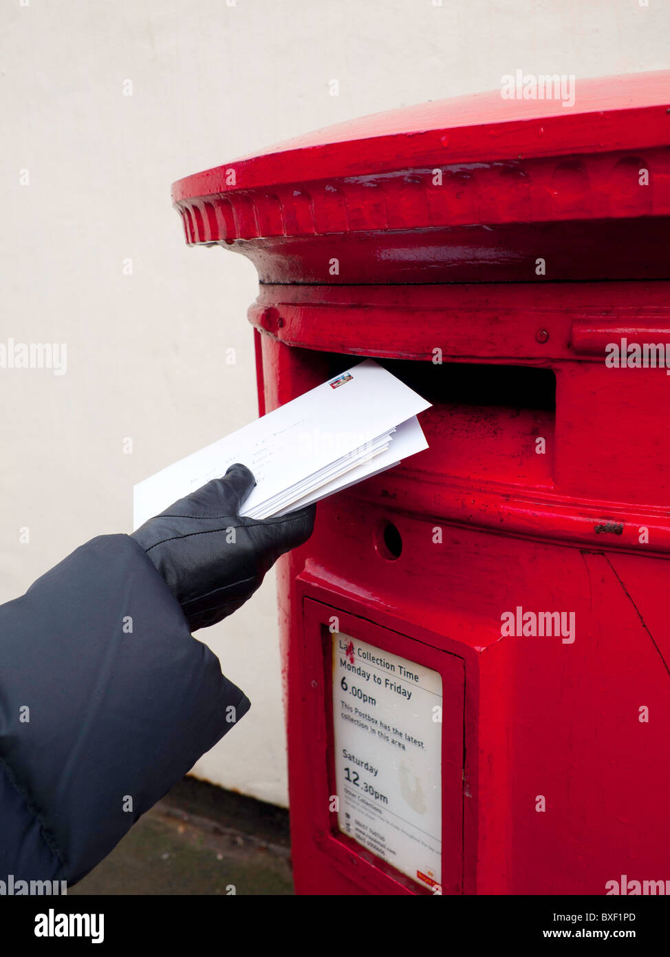 Buchen ein Bündel von Mail in einem traditionellen britischen rot Royal Mail Briefkasten Stockfoto