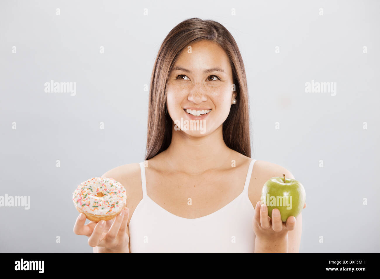 Frau hält einen Donut und ein Apfel Stockfoto