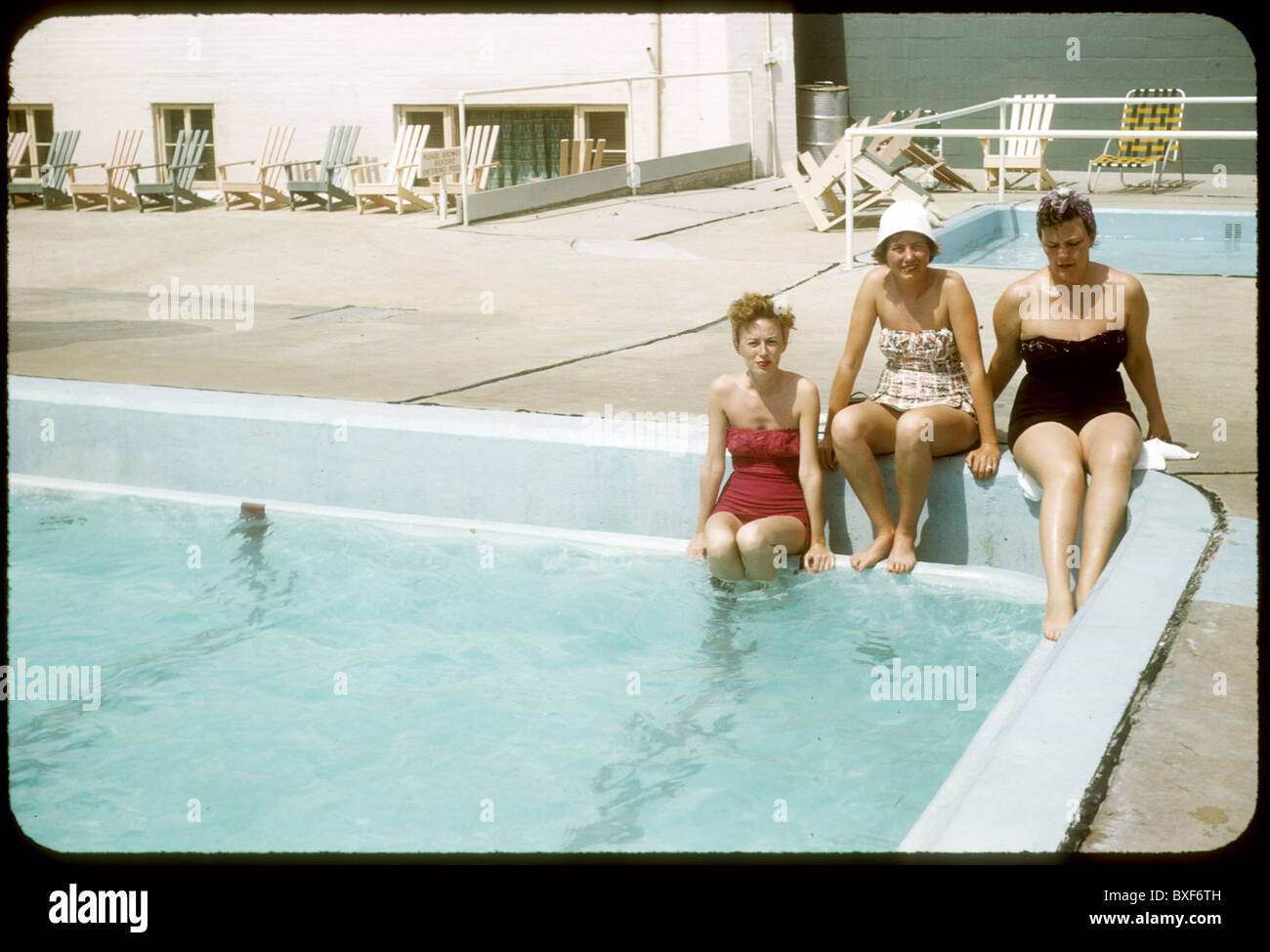 Drei Frauen sitzen am Rand des Motel Hotel Swmimming Pool Mode Badeanzug Badeanzug 1959s Mode der 1950er Jahre Tag Sommer fallen Stockfoto
