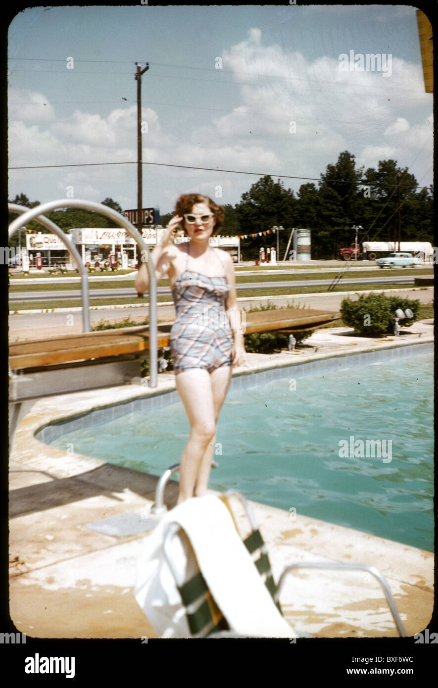 Modische Frau mit weißen Sonne Brille 1959 1950s stand neben Schwimmbad Motel Architektur posiert Tag vertikal Stockfoto