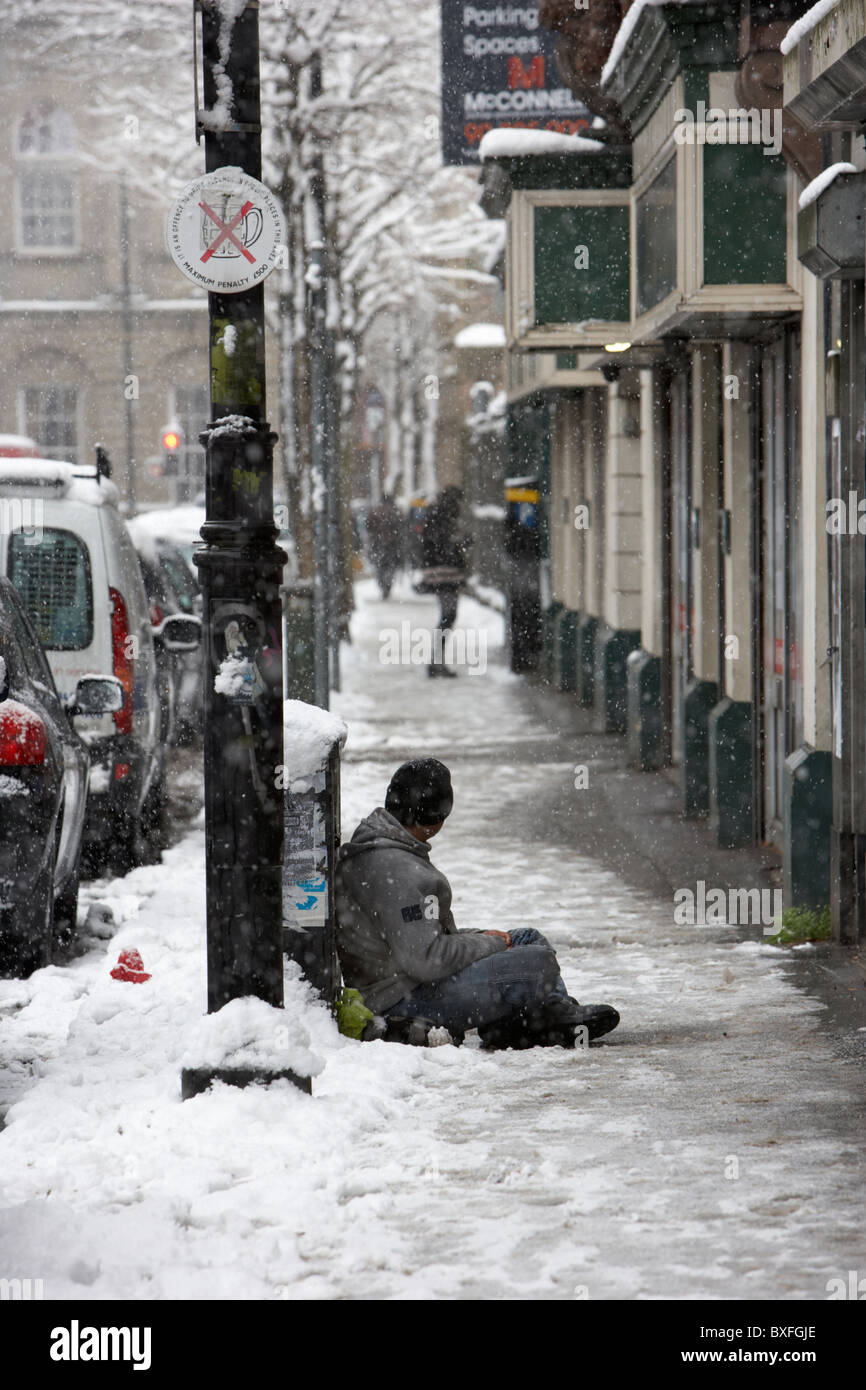 Straße Bettler sitzen im Schnee an einem kalten verschneiten Winter Tag Belfast Nordirland Stockfoto
