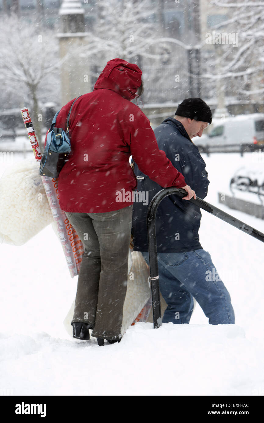 paar, Weihnachts-shopping zu Fuß hinunter Schritte an einem kalten verschneiten Winter Tag Belfast Nordirland Stockfoto
