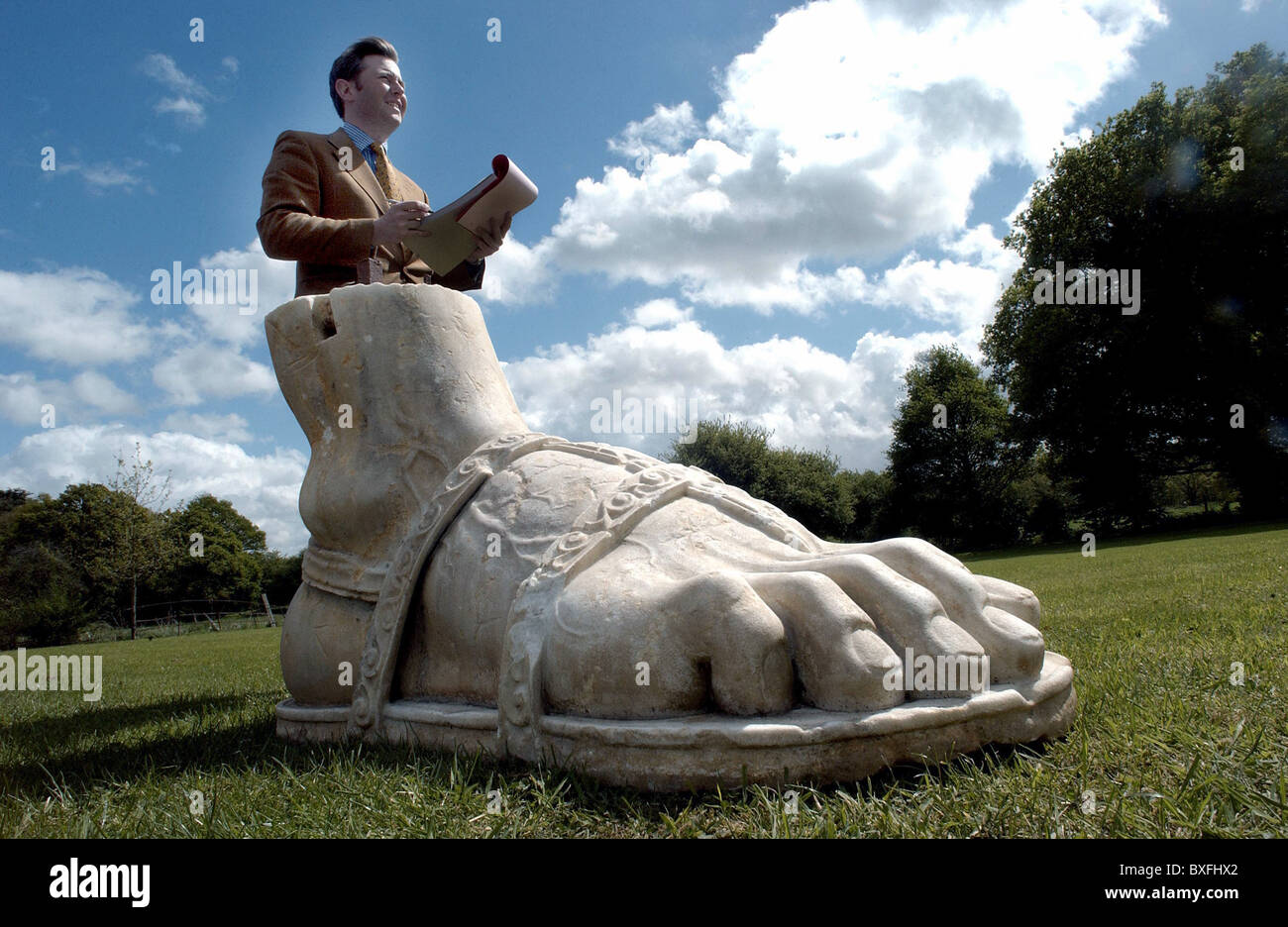 Eine Sotheby Auktionator mit einem gigantischen Marmor Fuß aus einer römischen Statue bei einem Verkauf der Garten Statuen Stockfoto