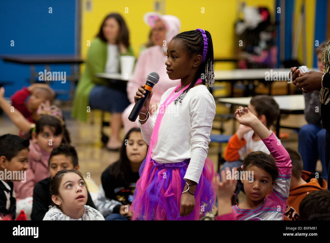 3. Klasse afroamerikanische Mädchen nutzt Mikrofon Frage während Kinderbuchautorin Derrick Barnes Programm an ihrer Schule Stockfoto