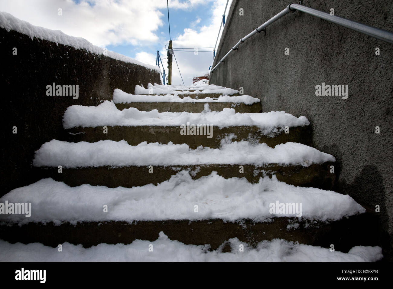 Eine Reihe von Außentreppe mit Schnee bedeckt. Es ist ein Handlauf an der rechten Wand. Die linken Wand ist mit Schnee gekrönt. Stockfoto