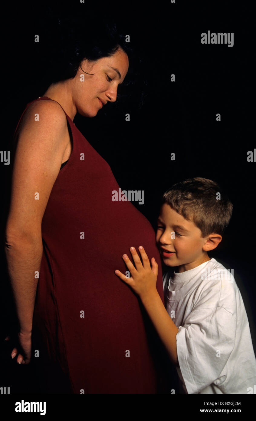 Schwangere Frau mit ihrem Sohn die Mutter Bauch halten. Stockfoto