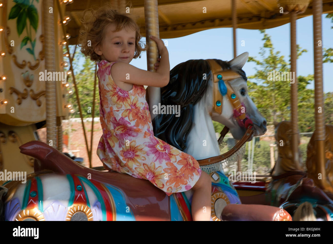 Junges Mädchen vorstellen, selbst Reiten auf ein echtes Pferd auf eine Karussellfahrt in einem Freizeitpark. Stockfoto