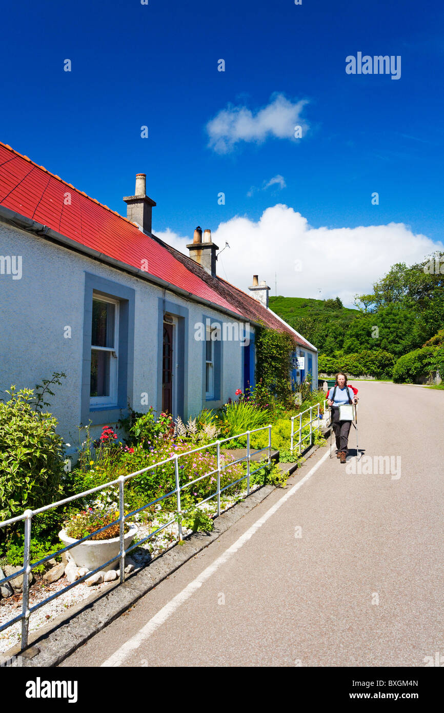 Ein Spaziergänger vorbei durch das Dorf hebt auf die Kintyre Weg Stockfoto