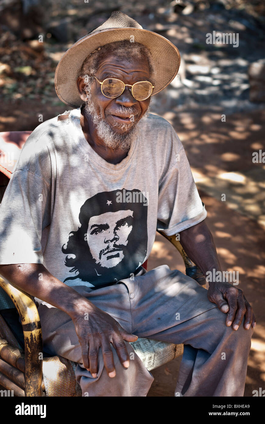 Alter Mann mit einem Che Guevara T-Shirt, Strohhut und Gläser auf der Suche nach der Kamera, Chinotimba, Zimbabwe, Afrika. Stockfoto