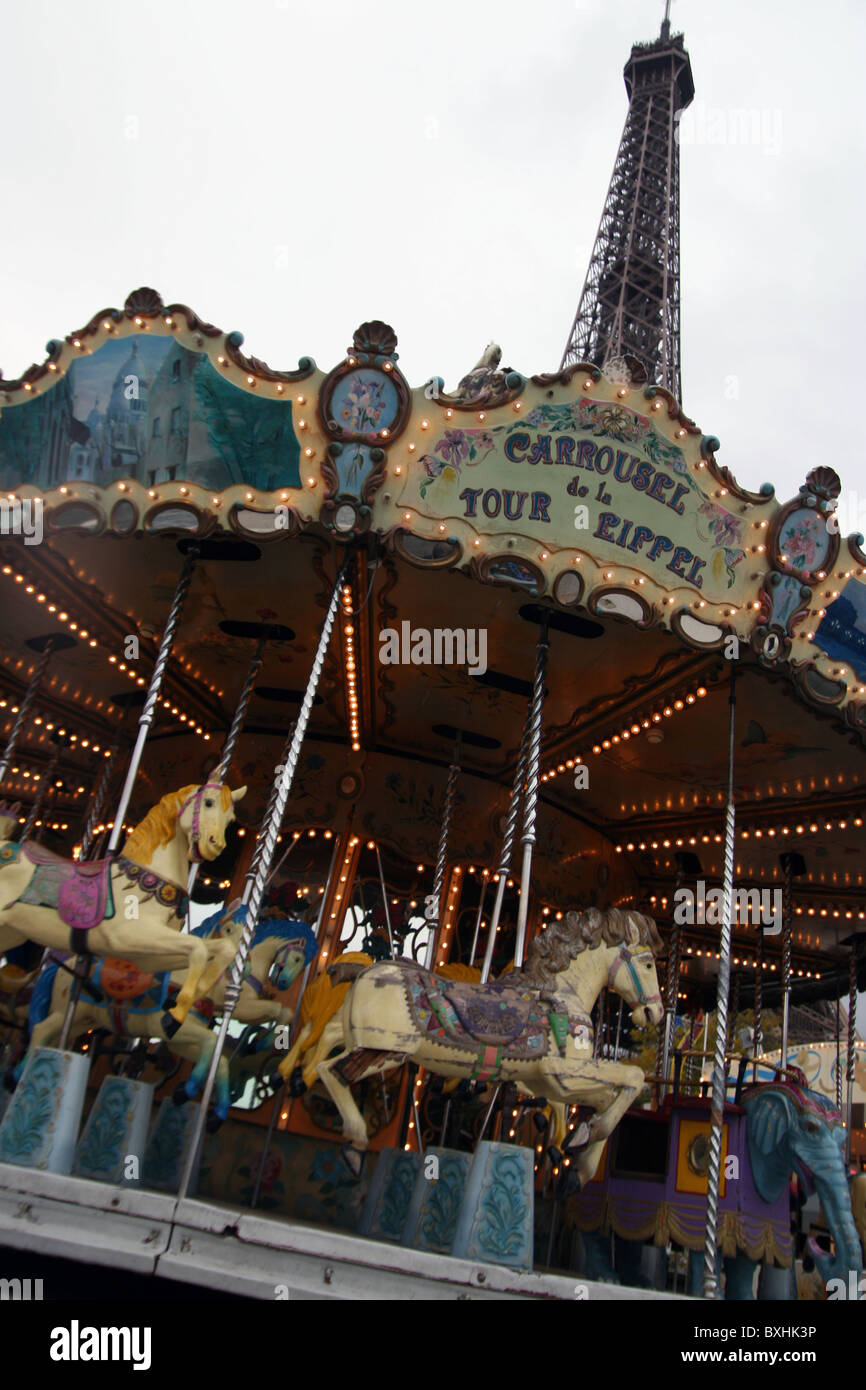 Ein Karussell dreht sich zusammen mit dem Eiffel-Turm im Hintergrund. Stockfoto