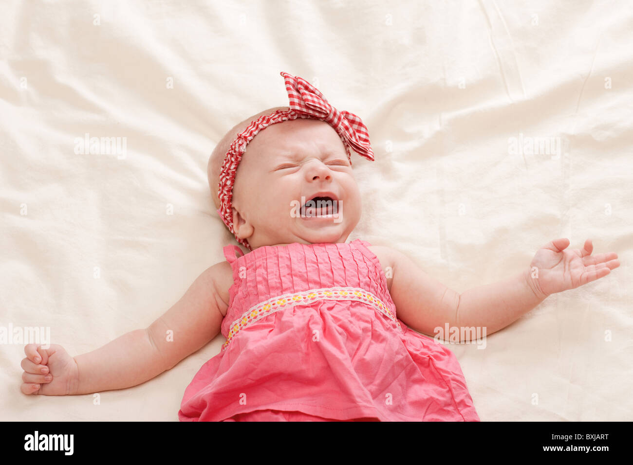 Weinen und Gestikulieren zehn Wochen alten Babymädchen auf Bett Stockfoto