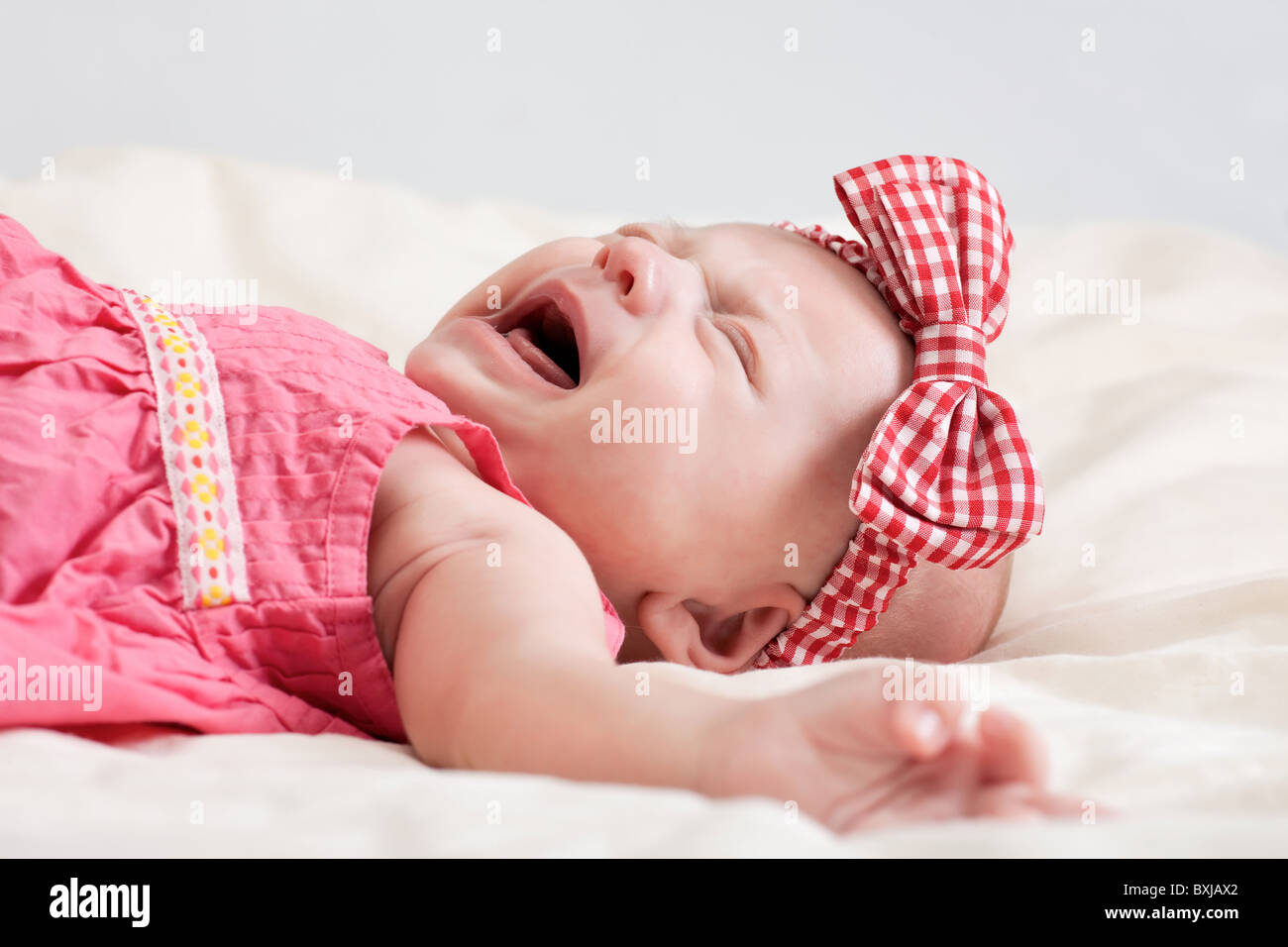 Zehn Wochen alten Babymädchen auf Bett Weinen Stockfoto