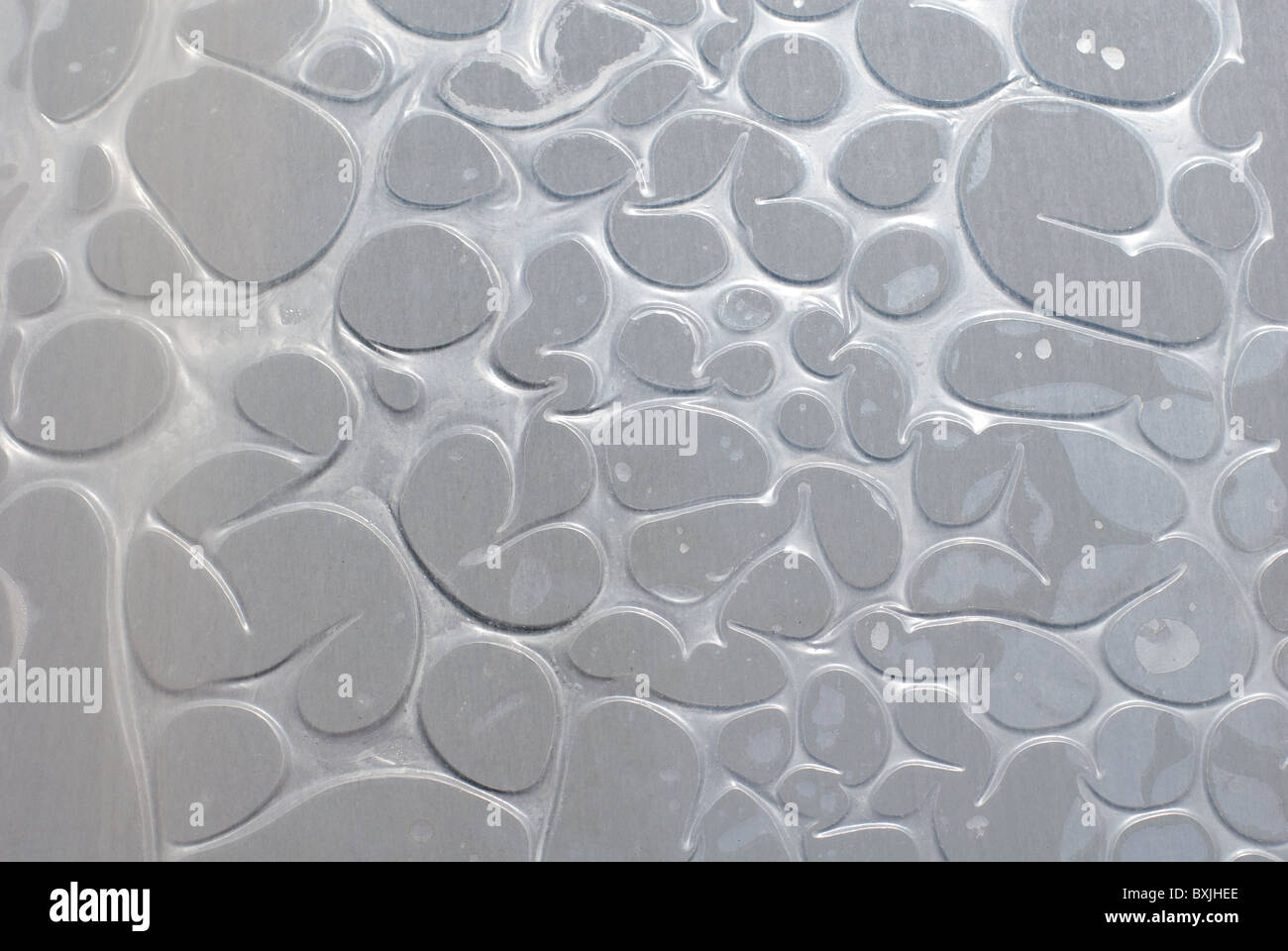 sprudelnde grauen Kunststoff-Folie auf einer Glasoberfläche Stockfoto