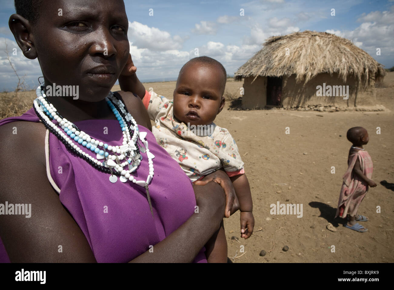 Eine Massai-Frau hält ein Baby vor ihrem Haus im ländlichen Norden von Tansania, Ostafrika. Stockfoto