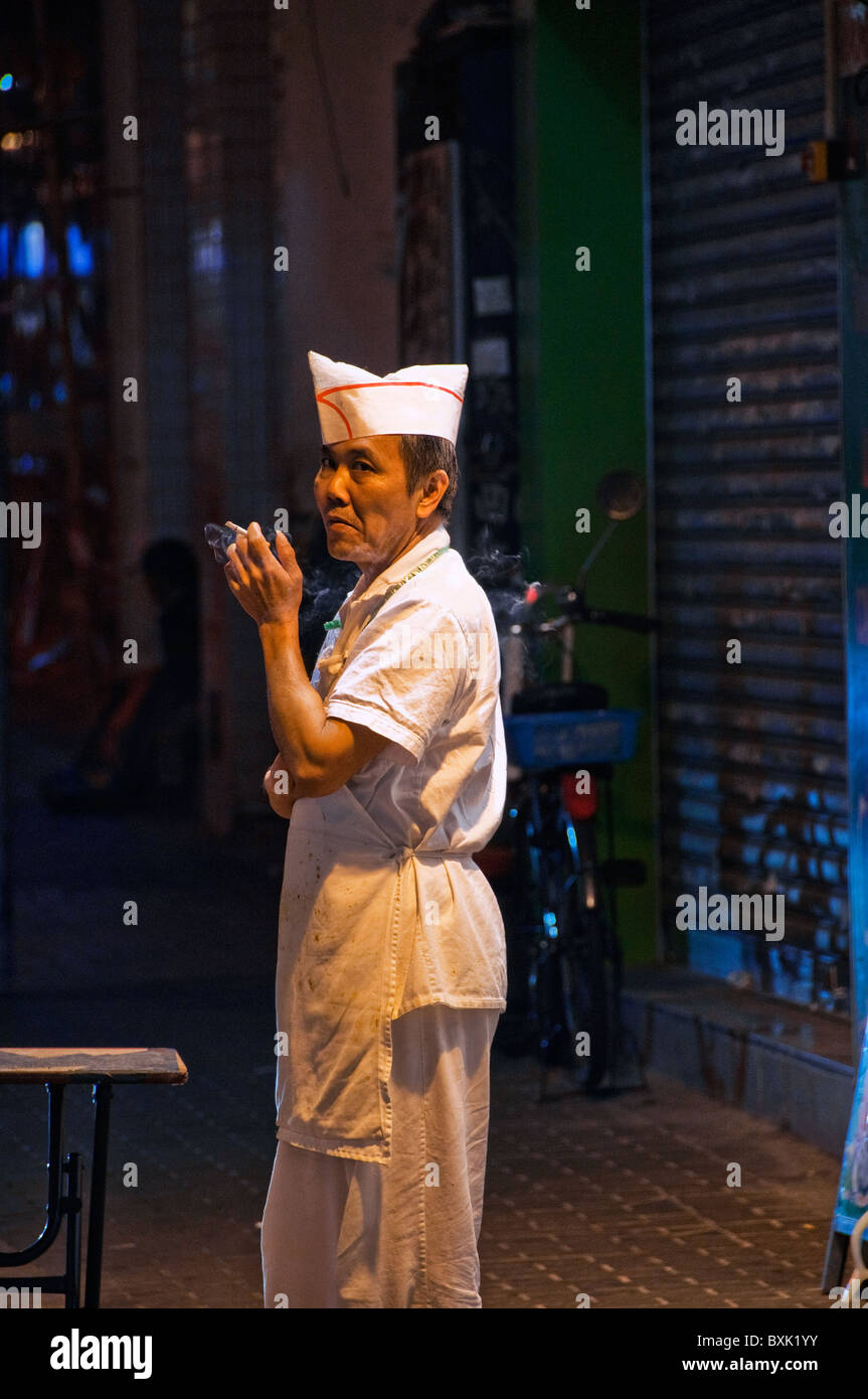 Asiatischen männlichen Küche Arbeiter stehen außerhalb Restaurants Rauchen einer Zigarette in der Innenstadt von Hongkong China Stockfoto