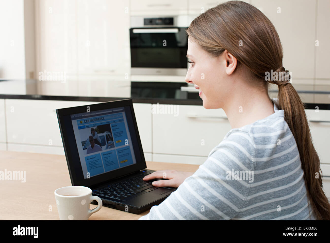 Junge Frau, die Kfz-Versicherung auf Laptop betrachten Stockfoto