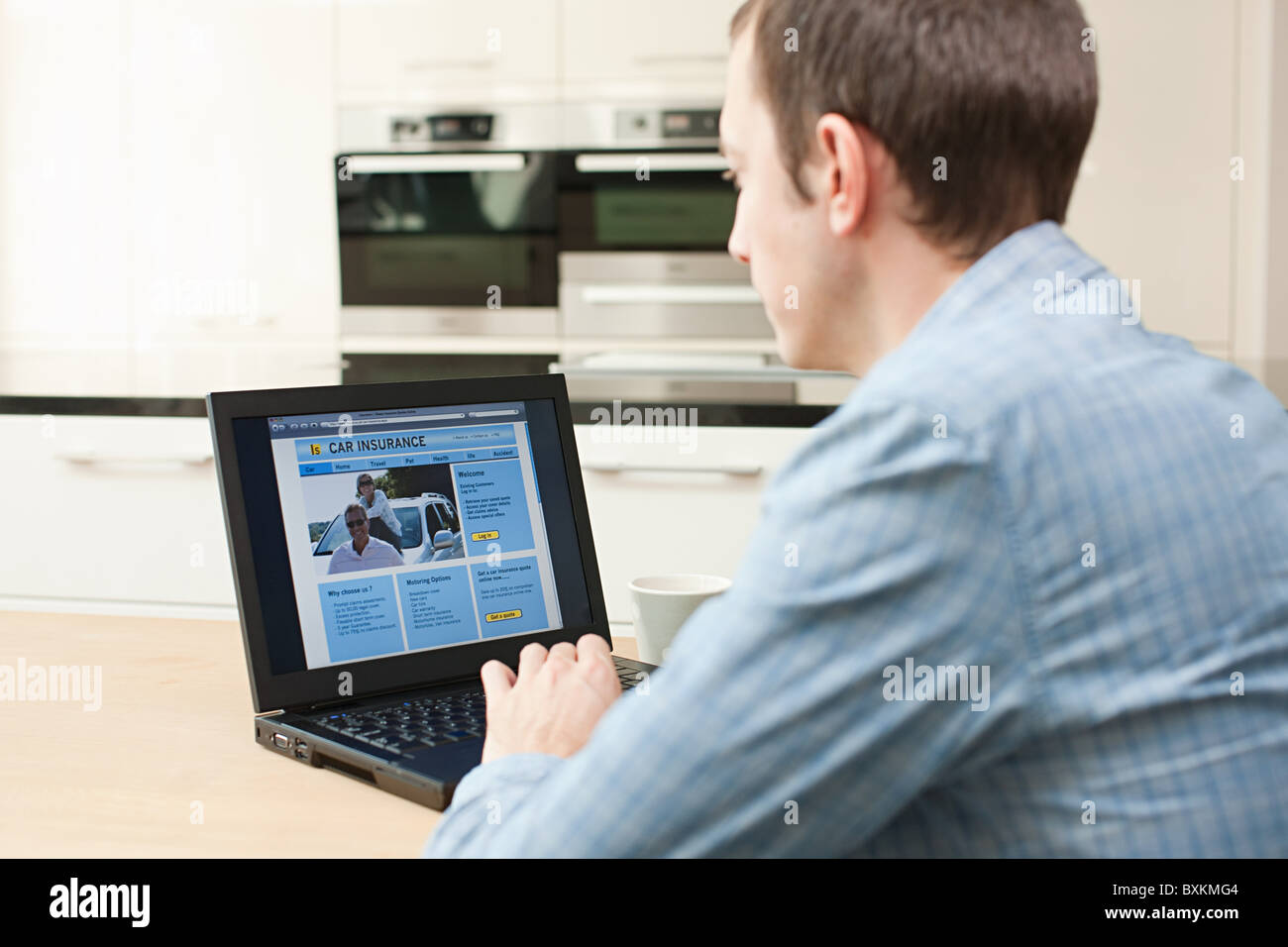 Junger Mann, Blick auf Kfz-Versicherung auf laptop Stockfoto