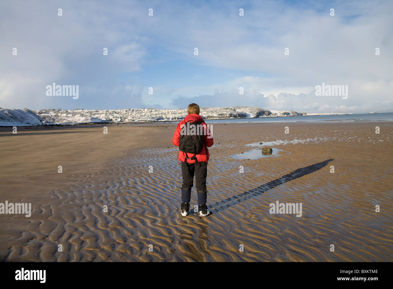 Benllech ISLE OF ANGLESEY Wales UK Dezember Frau entlang der Blauen Flagge ausgezeichneten Strand an einem schönen Wintertag allein auf dem einsamen Strand außerhalb der Saison Stockfoto