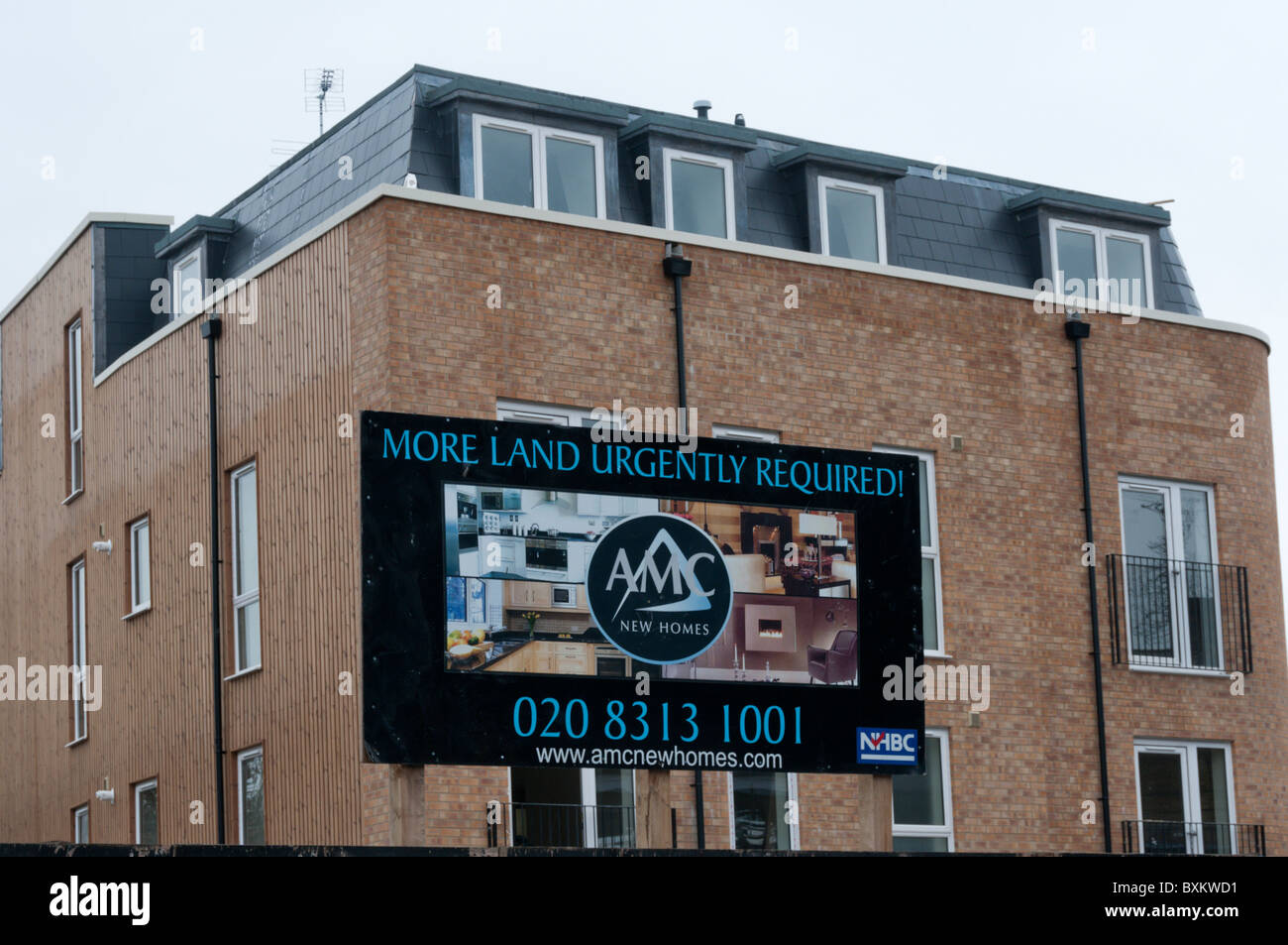 Ein Schild sagt "mehr Land dringend erforderlich!" auf einem Wohngebäude-Gelände in Süd-London. Stockfoto