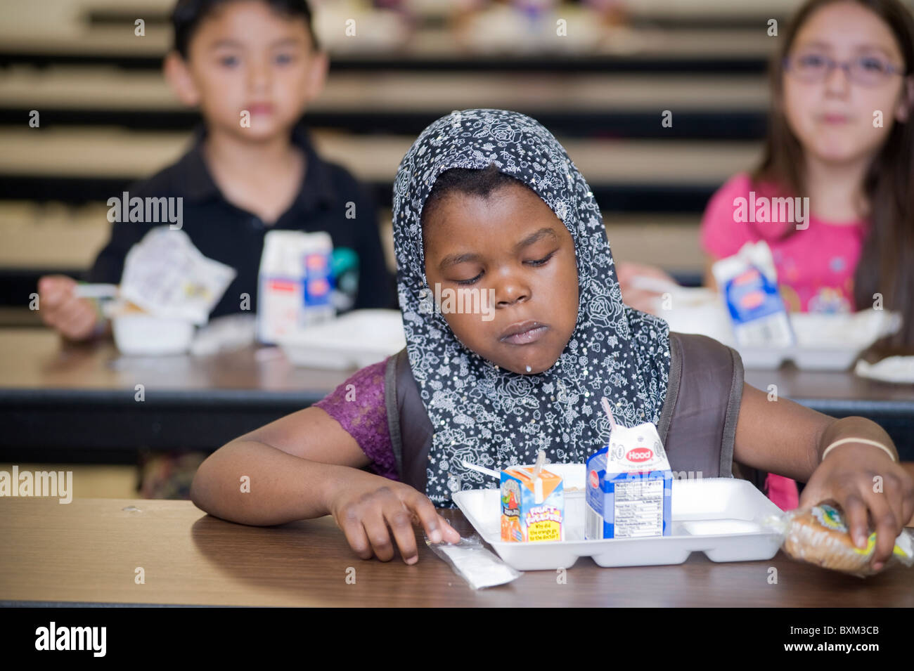 Grundschule Mädchen und Jungen zu Mittag essen und interagieren Sie mit Kommilitonen an der Buche Elementary School in Manchester NH Stockfoto