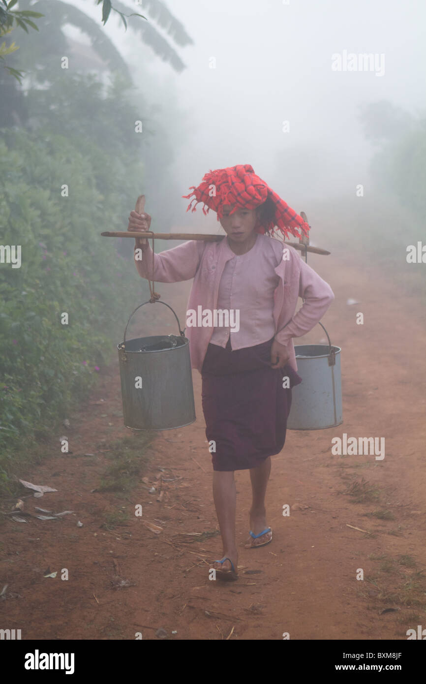 burmesische Indianerin tragen Eimer Wasser im Nebel Stockfoto