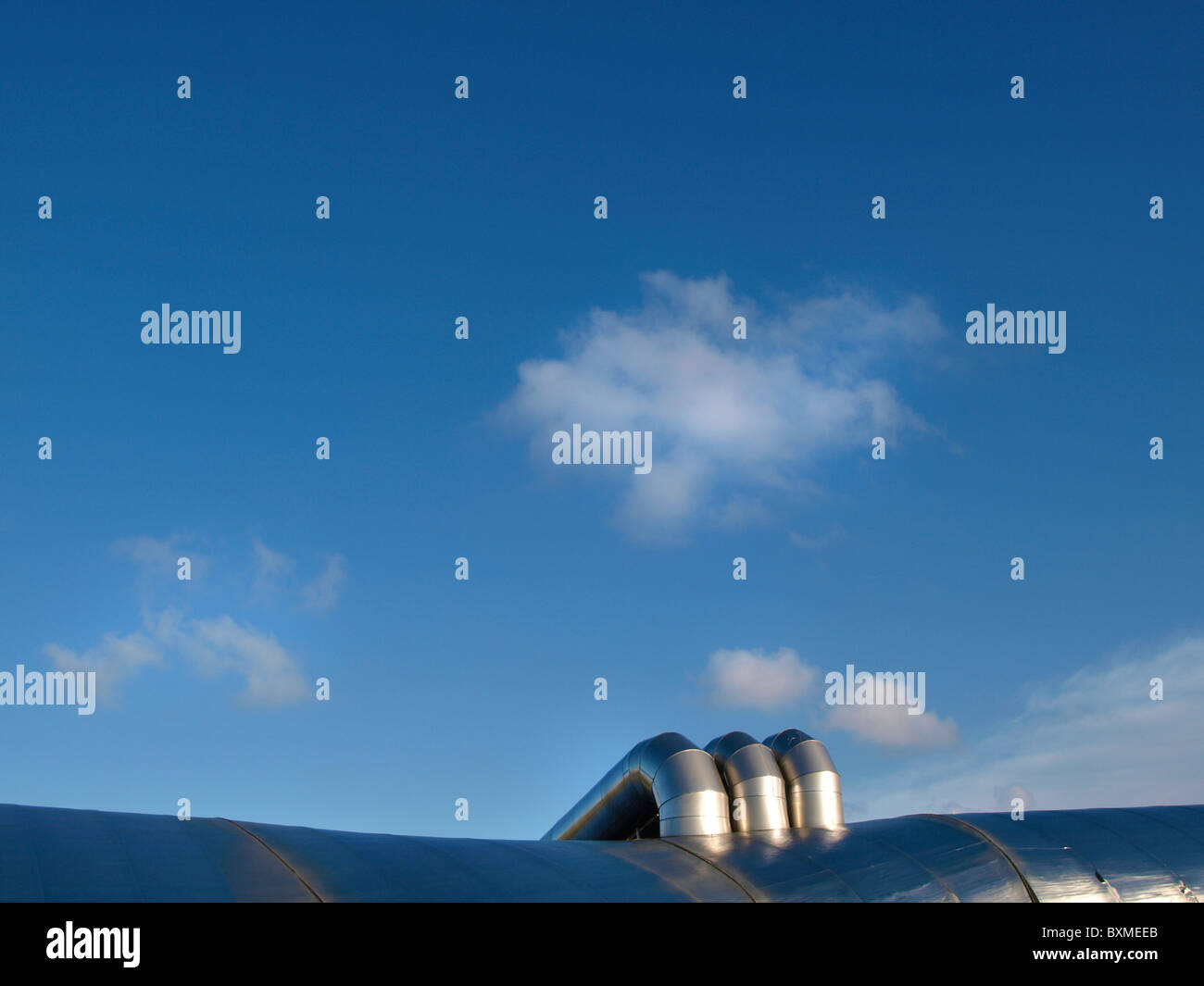 halb abstraktes Bild von moderner Architektur Metall Blob mit Rohren und blauer Himmel mit kleinen Wolke Stockfoto