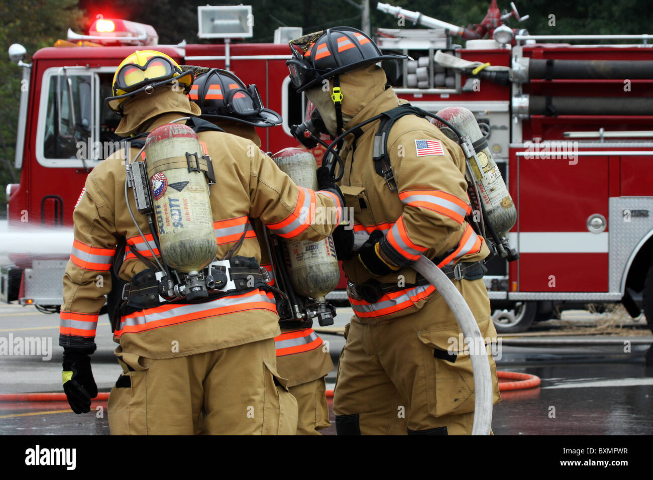 Ein Team der Feuerwehr mit einer Schlauchleitung, ein Feuer zu löschen Stockfoto