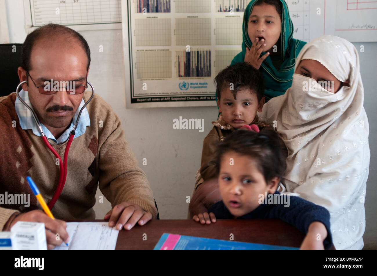 Pakistan nach der Flut. Ein Arzt untersucht einen Frau-Patienten, die von ihren Kindern umgeben ist Stockfoto