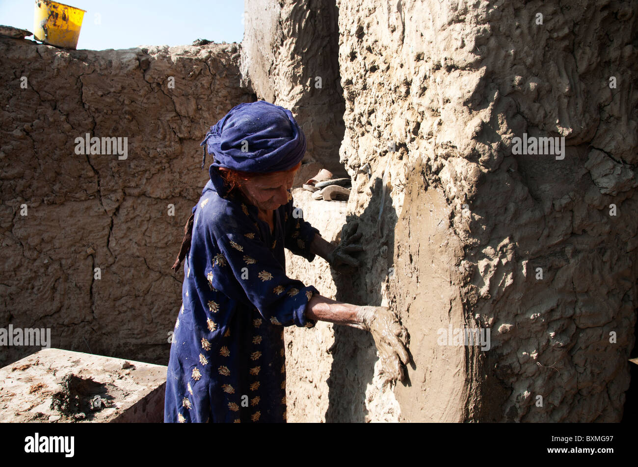 Kheshgi Lager für afghanische Flüchtlinge. Nach der Flut. 76 Jahre alten Safk Khalthoum Pflaster ihrem umgebauten Haus mit Schlamm. Stockfoto