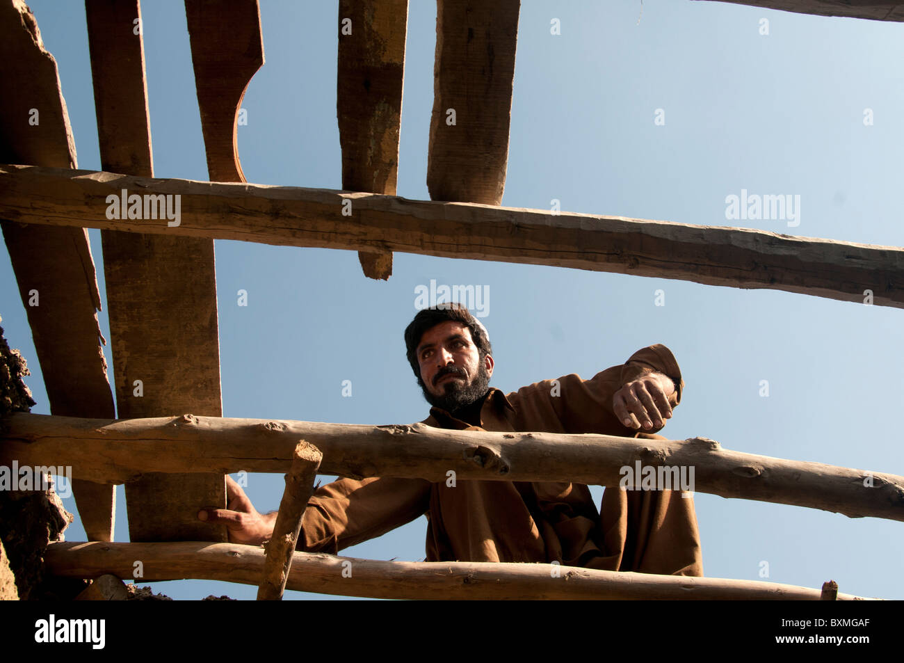 Pakistan nach der Flut... Kheshgi Lager für afghanische Flüchtlinge. Mann, der ein Dach für sein Haus aus alten Dielen. Stockfoto