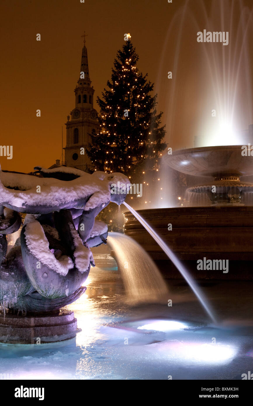 Schnee und Eis überkrustet Brunnen auf dem Londoner Trafalgar Square mit dem berühmten Weihnachtsbaum. Stockfoto