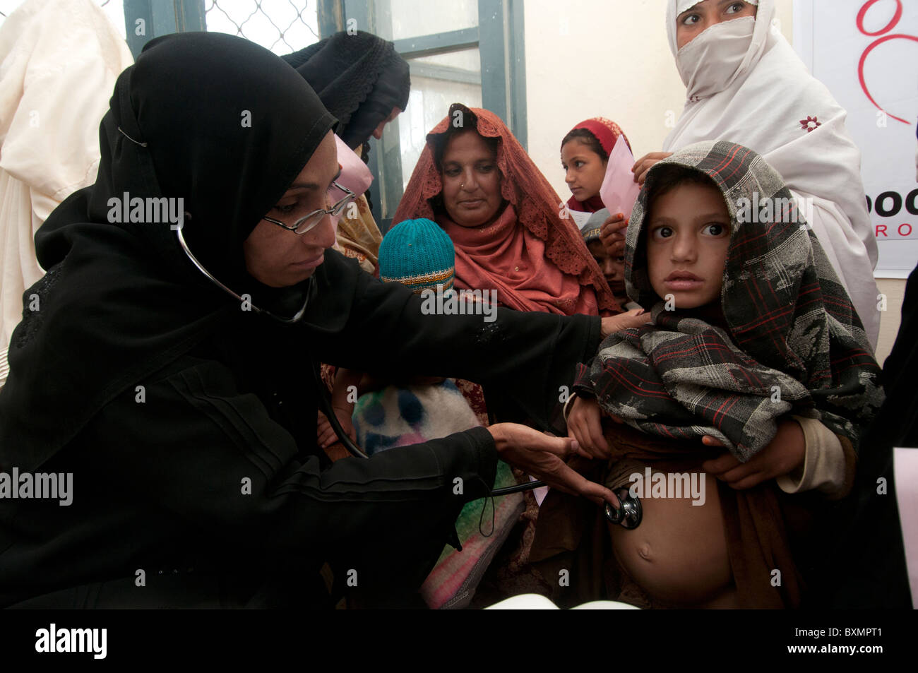 Pakistan nach der Flut. Dr. Hasiba Tarin untersucht einen Patienten, ein Kind mit einem erweiterten Bauch und Brust-Infektion Stockfoto