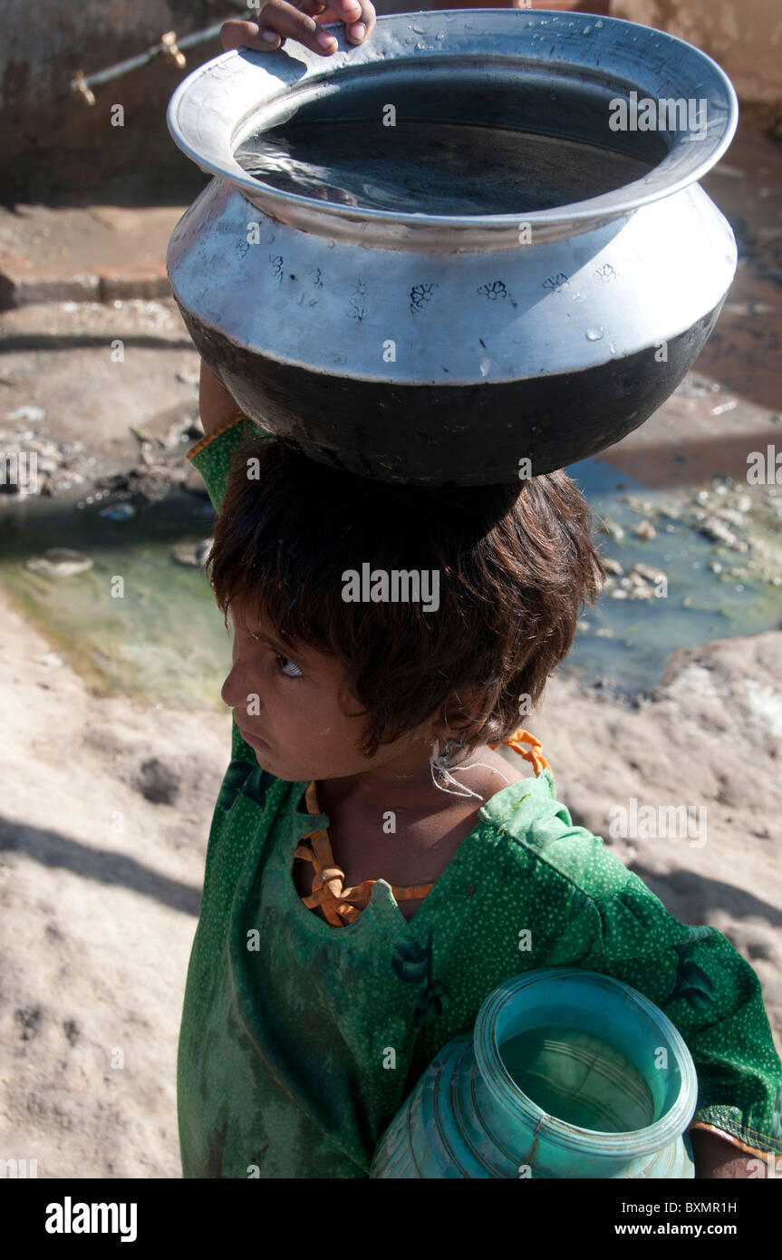 Pakistan nach der Flut. Junges Mädchen mit Topf mit Wasser auf dem Kopf Stockfoto