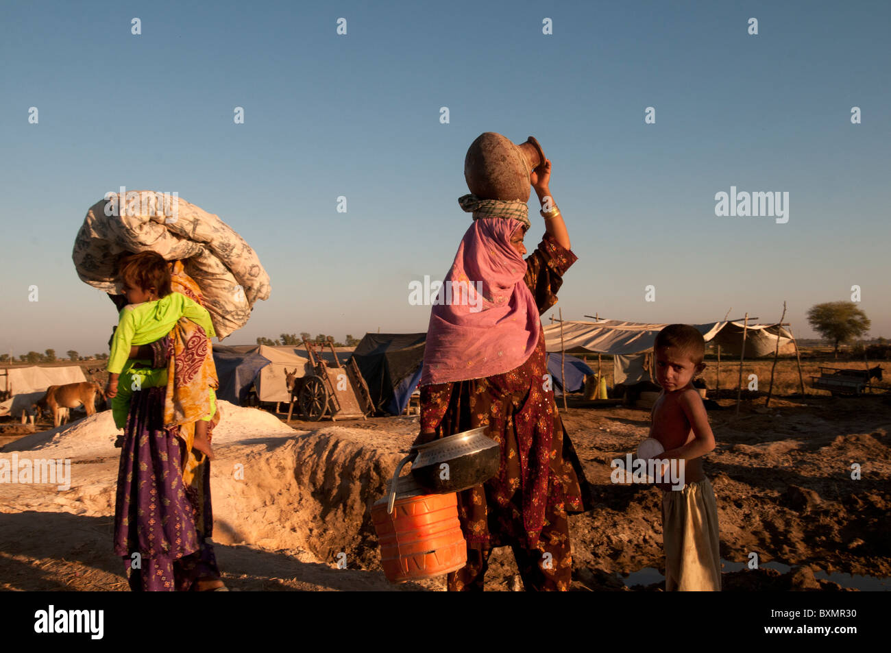 Sindh Provinz Shaddat Kot. Nach der Flut. Tankstelle-Lager für Vertriebene. Zwei Frauen gehen mit ihren Besitztümern Stockfoto