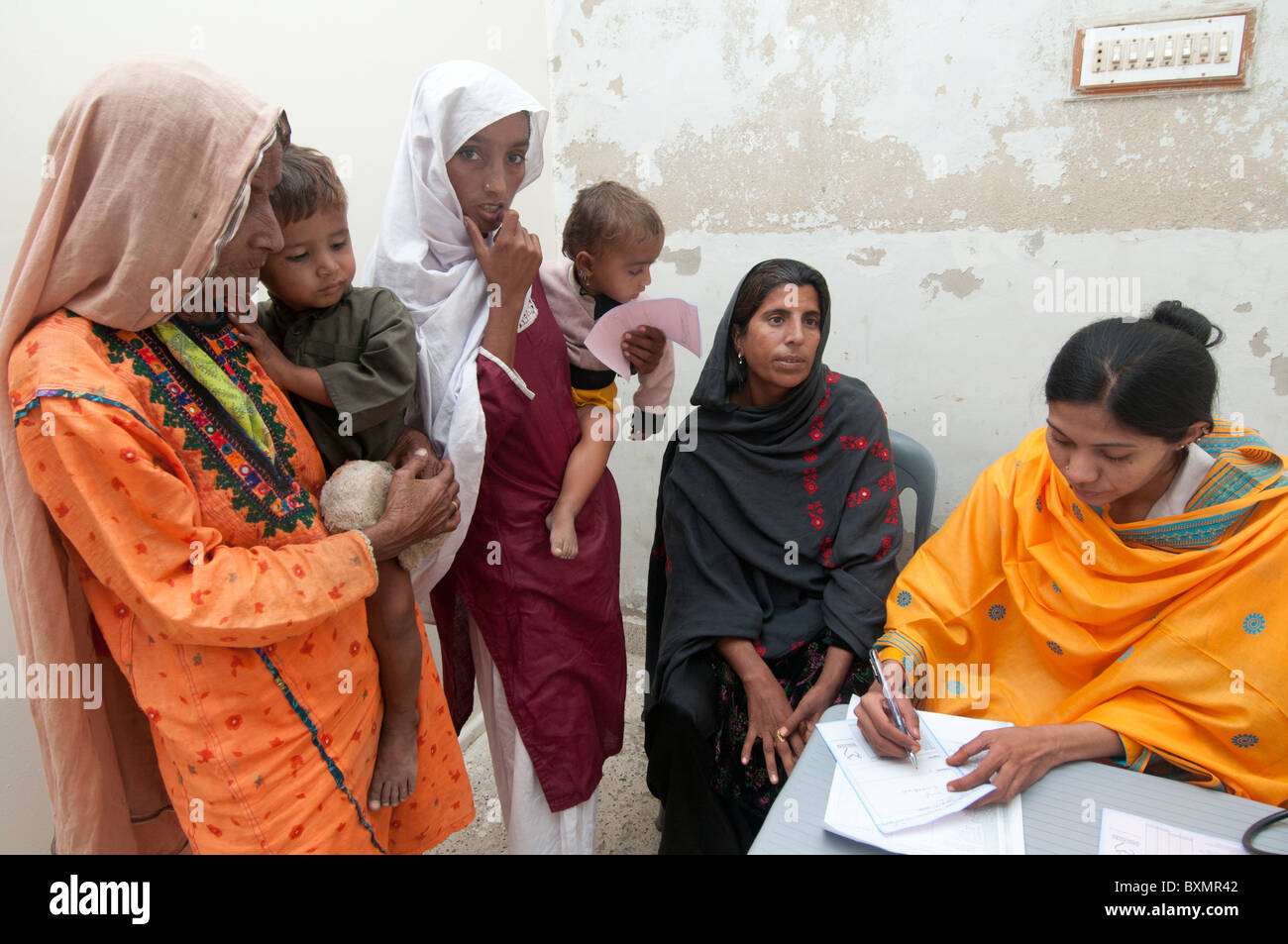 Pakistan nach der Flut. Arzt Sahira Bano untersucht einen Patienten beobachtet von ihrer Familie Stockfoto