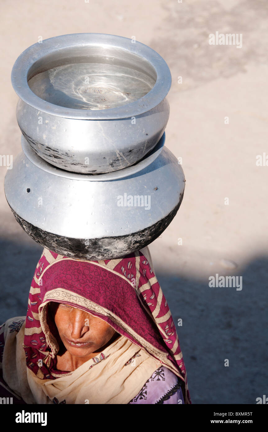 Pakistan nach der Flut. Lager für Vertriebene. Frau, die einen Topf mit Wasser auf dem Kopf. Stockfoto